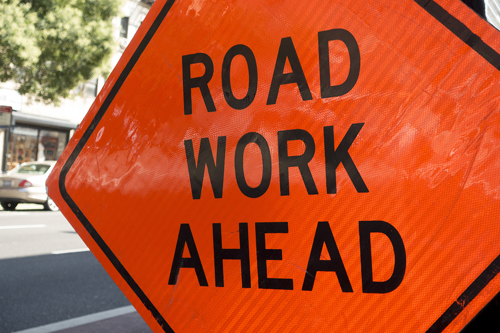 diamond shaped orange red reflector street sign that reads road